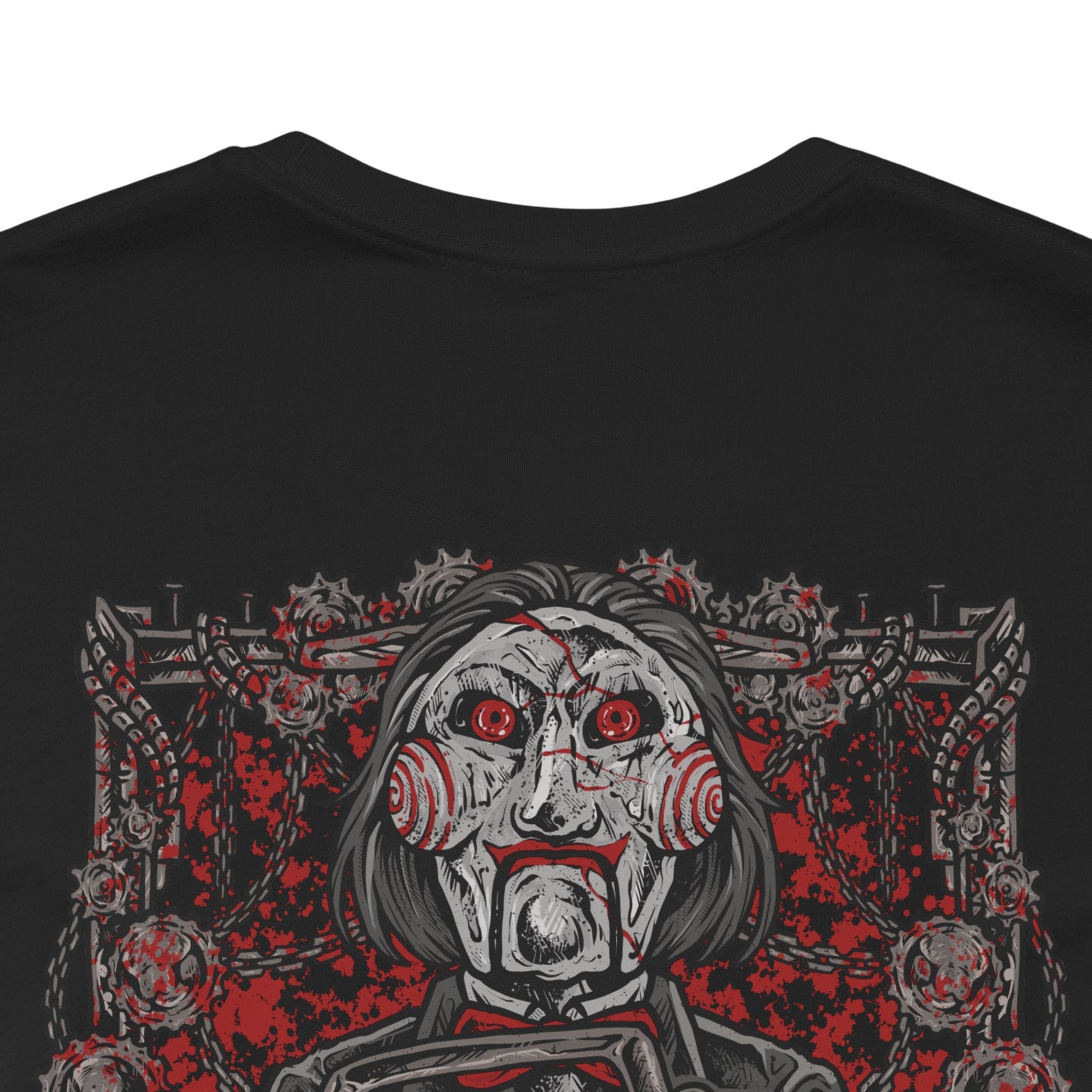 Image 7 of a T-Shirt artwork depicting Billy the Puppet emerging from darkness with his tricycle positioned beneath a harsh spotlight. Shadows stretch across the floor while old television screens and mechanical traps fill the background. This design reflects the disturbing symbolism of Jigsaw’s messenger, embodying dread, manipulation, and the cruel tests that define the Saw franchise.