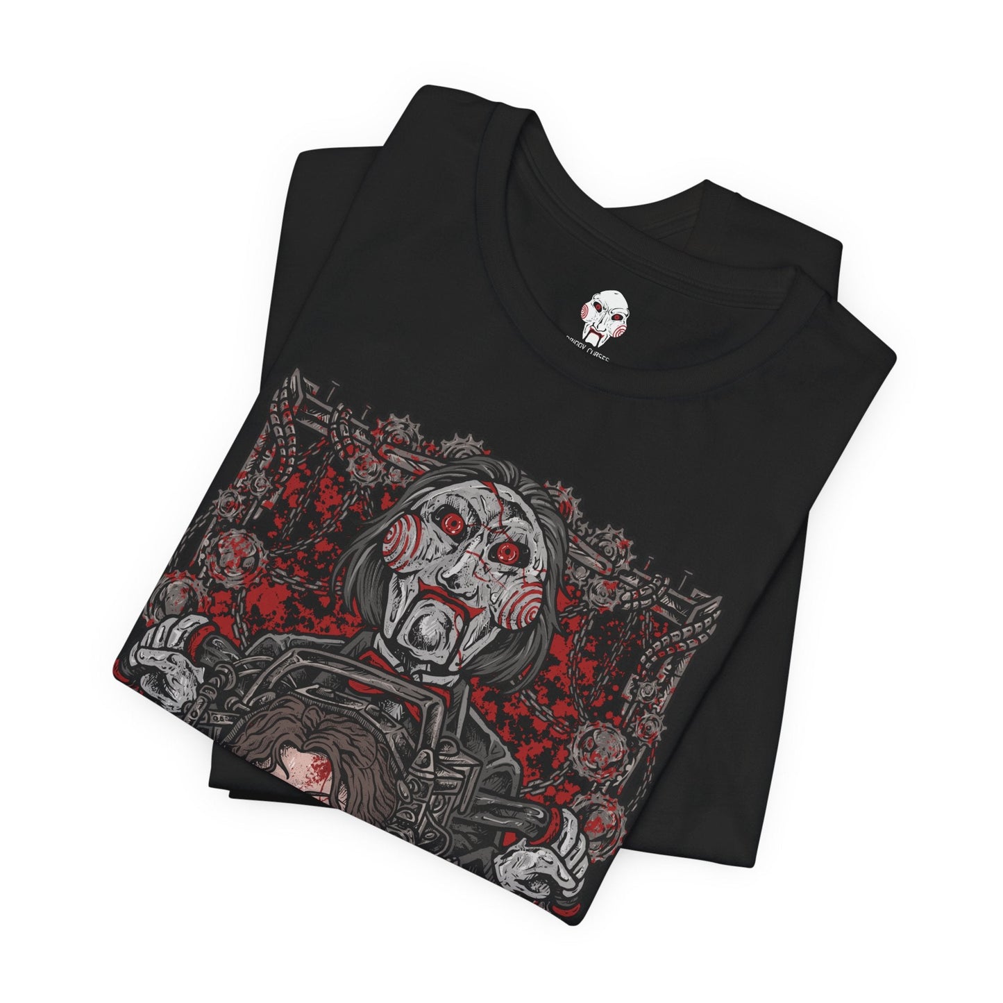 Image 5 of a T-Shirt design of Billy the Puppet from Saw, seated on his tricycle in a dimly lit room surrounded by rusted chains, flickering lights, and blood-stained walls. His pale face, spiraled red cheeks, and unblinking eyes create an unsettling presence. The design captures the psychological horror of Jigsaw’s games and the fear of being forced to choose between survival and sacrifice.