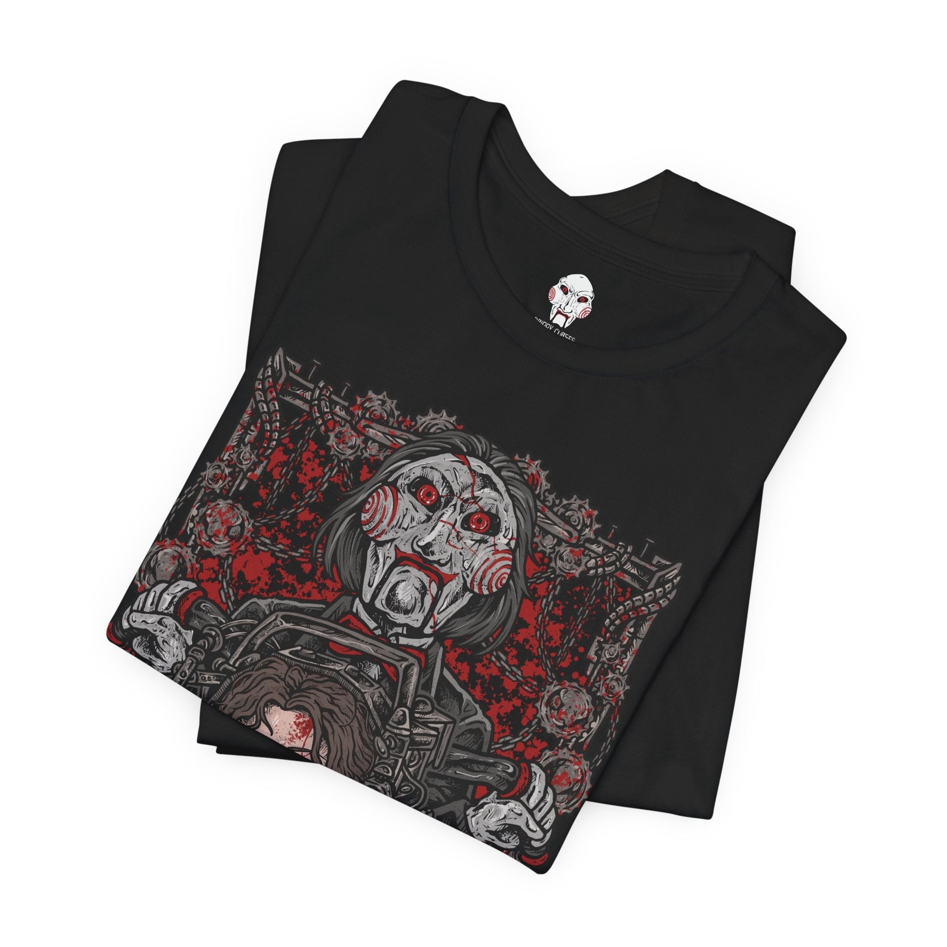 Image 5 of a T-Shirt design of Billy the Puppet from Saw, seated on his tricycle in a dimly lit room surrounded by rusted chains, flickering lights, and blood-stained walls. His pale face, spiraled red cheeks, and unblinking eyes create an unsettling presence. The design captures the psychological horror of Jigsaw’s games and the fear of being forced to choose between survival and sacrifice.
