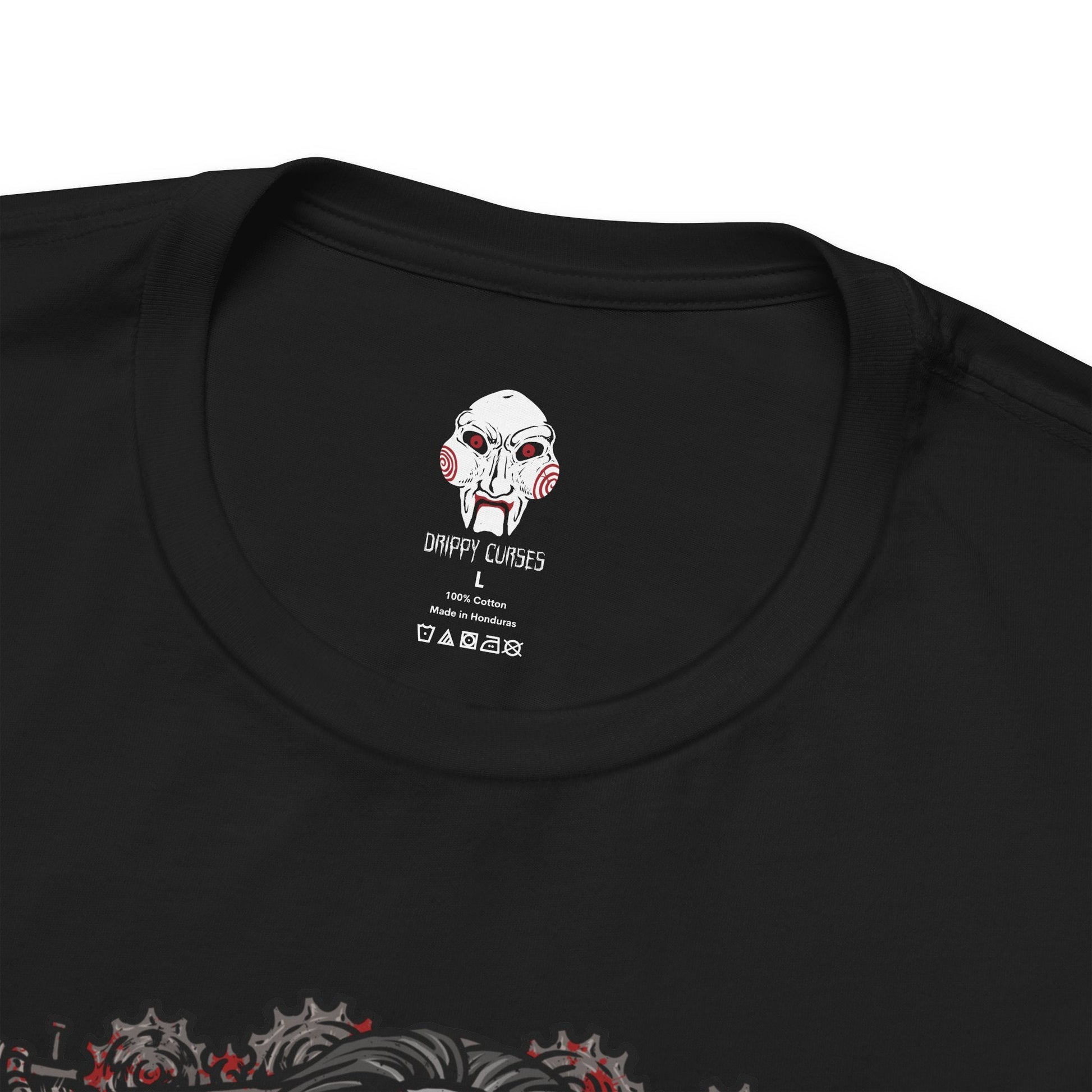 Folded T-Shirt design of Billy the Puppet from Saw, seated on his tricycle in a dimly lit room surrounded by rusted chains, flickering lights, and blood-stained walls. His pale face, spiraled red cheeks, and unblinking eyes create an unsettling presence. The design captures the psychological horror of Jigsaw’s games and the fear of being forced to choose between survival and sacrifice.