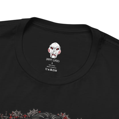 Folded T-Shirt design of Billy the Puppet from Saw, seated on his tricycle in a dimly lit room surrounded by rusted chains, flickering lights, and blood-stained walls. His pale face, spiraled red cheeks, and unblinking eyes create an unsettling presence. The design captures the psychological horror of Jigsaw’s games and the fear of being forced to choose between survival and sacrifice.