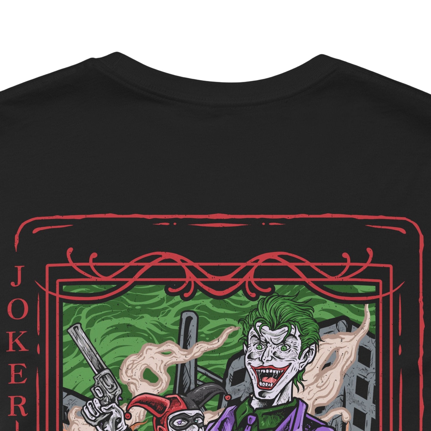 Image 7 of a T-Shirt artwork depicting the Joker and Harley Quinn embracing chaos in the streets of Gotham City, with explosions, scattered poker chips, and purple-green smoke filling the background. The Joker flourishes a deck of cards while Harley balances her signature bat across her shoulders. This design reflects madness, rebellion, and the twisted bond that blurs the line between obsession, loyalty, and destruction.