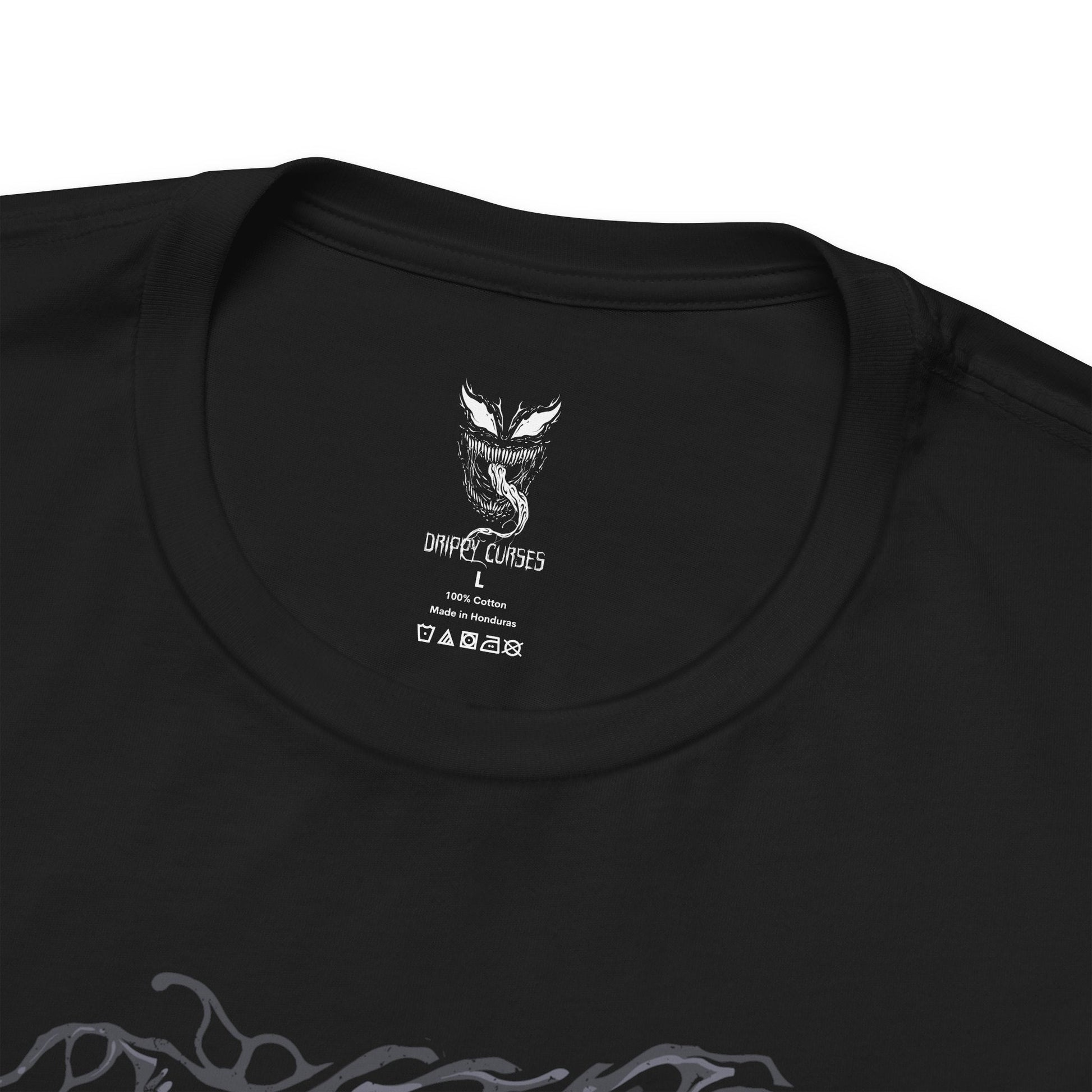 Folded T-Shirt design of Venom from Marvel, towering in darkness as the black symbiote stretches across his massive muscular body. Sharp teeth glisten beneath glowing eyes while his long tongue curls outward, dripping saliva onto cracked pavement below. The design captures Venom’s monstrous power, predatory nature, and the terrifying fusion between alien symbiote and human host.