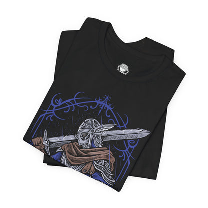 Folded T-shirt design of Wylder from Elden Ring Nightreign, a hardened Nightfarer warrior standing beneath a storm-dark sky as the Night’s Tide spreads across Limveld. His worn armor and rune-etched blade glow with faint spectral light while distant monsters emerge from the darkness. The design captures a lone champion rising against the Nightlord’s spreading corruption.